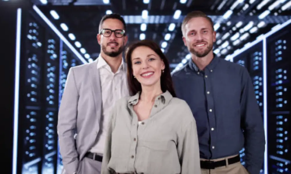 Three colleagues facing the camera while in a server room.